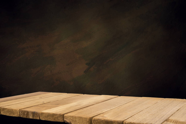 Enfoque seleccionado mesa de madera marrón vacía y textura de pared o imagen de fondo borrosa de pared de ladrillo negro viejo. para su fotomontaje o visualización del producto - Foto, imagen
