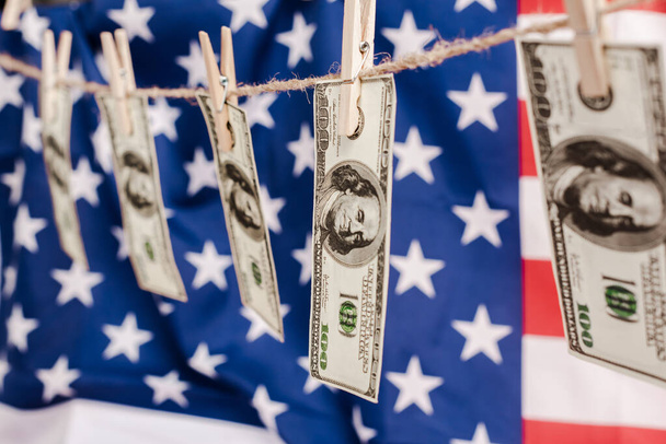 selective focus of dollar banknotes hanging on rope on american flag background, coronavirus concept - Photo, Image