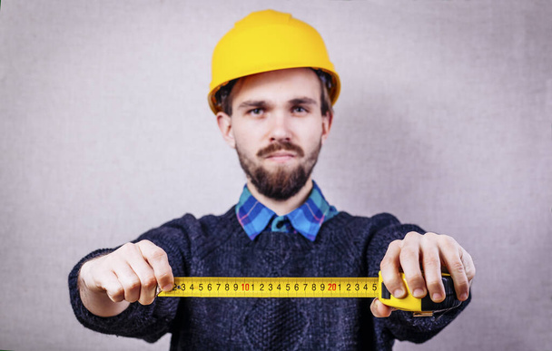 young builder with yellow tape measure - Valokuva, kuva