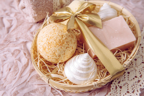 Natural bamboo material gift basket filled with shredded wood excelsior with various spa bathroom products, pink soap bar, bath bomb, natural sponge on vintage light pink background. Beauty present. - Photo, Image
