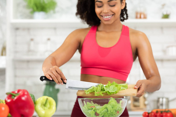 Hermosa chica negra joven preparando ensalada de verduras en casa
 - Foto, Imagen