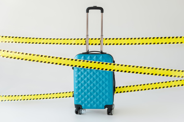 niebieska walizka w żółtej i czarnej kasecie ostrzegawczej o zagrożeniach na białej koncepcji koronawirusa - Zdjęcie, obraz