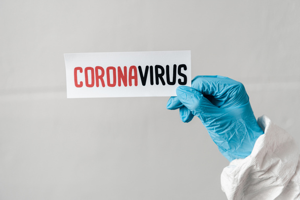 vista recortada de la persona en guante de látex con tarjeta coronavirus
 - Foto, Imagen