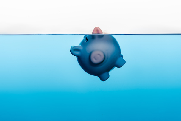 Sparschwein unter blauem Wasser isoliert auf weißem, Coronavirus Krisenkonzept - Foto, Bild