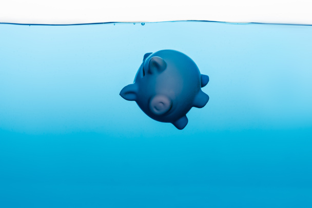 piggy τράπεζα πηγαίνει κάτω από μπλε νερό απομονώνονται σε λευκό, έννοια κρίση coronavirus - Φωτογραφία, εικόνα