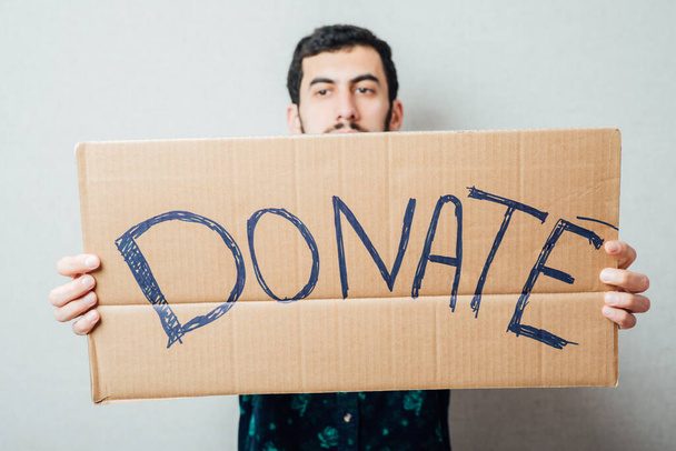young man showing board with text: Donate - Photo, image