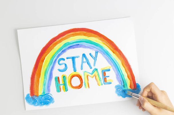 Kid painting during quarantine at home. Rainbow with words Stay at home. Social media campaign for coronavirus prevention - Photo, Image