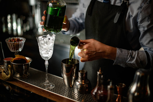Professional barman using beaker pours drink into shaker - 写真・画像
