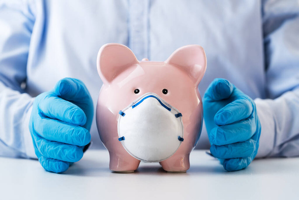 Close-up Of A Human Hand Protecting Pink Piggy Bank On White Desk - Photo, image
