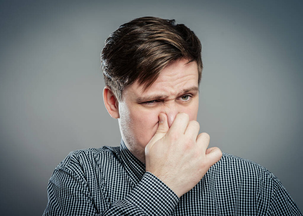 Man holding his nose against a bad smell - Fotó, kép