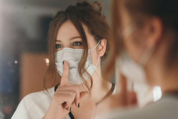 Kobieta o jasnych włosach zakłada maskę medyczną w celu ochrony przed wirusem - Zdjęcie, obraz