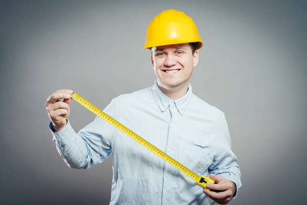 The builder in a helmet with a meter - Φωτογραφία, εικόνα