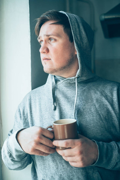 Handsome guy with cup of tea in the hood - Фото, зображення