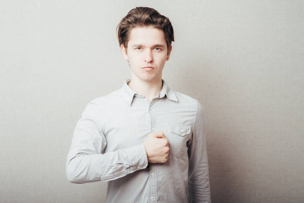 Young handsome man is swearing allegiance with his hand, fist on chest. Closeup portrait arrogant, self important, stuck up, napoleon complex, short man syndrome guy Emotion facial expression feeling - Foto, afbeelding