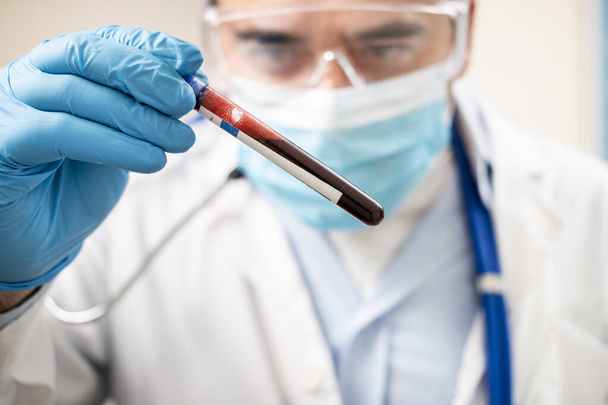 Vista de un médico sosteniendo una muestra de sangre de probeta ficticia, posiblemente infectada
. - Foto, imagen