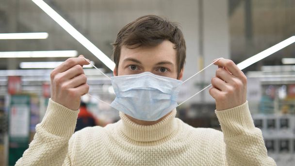 Un uomo in un supermercato sollevato di rimuovere la maschera medica. La pandemia del coronavirus e 'finita. La vita è meravigliosa
. - Foto, immagini