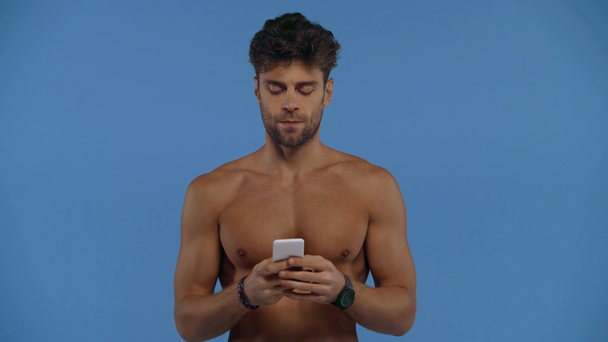 Komea paidaton mies puhuu selfie älypuhelimella eristetty sininen
 - Materiaali, video