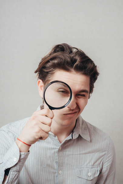young man looking through a magnifying glass - Photo, image