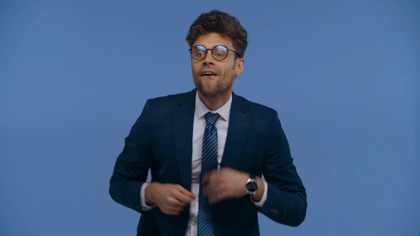 Junger Geschäftsmann im Anzug tanzt isoliert auf blauem Grund - Filmmaterial, Video