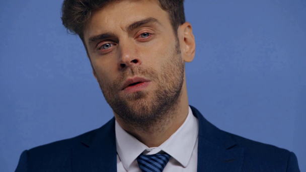 Όμορφος επιχειρηματίας κοιτάζοντας κάμερα απομονωμένη στο μπλε - Πλάνα, βίντεο