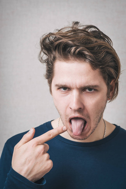 молодий чоловік з пальцем на язиці
 - Фото, зображення