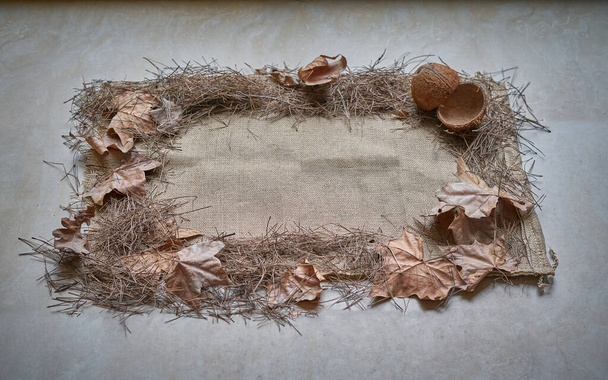 view of a rectangle made with bottom sackcloth on which are arranged in a frame, dry leaves and coconut shells in the upper left corner - Photo, Image