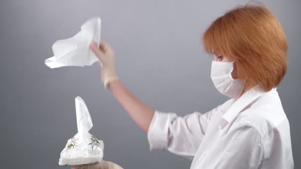 Жінка в медичній масці і рукавичках витягає паперові серветки з коробки з-під диспетчера на сірому фоні. 2019 Novel Coronavirus 2019-nCoV, концепт COVID-19. - Кадри, відео