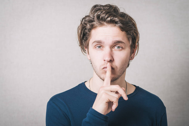 Man shows his finger to his mouth quiet. Gray background. - Fotoğraf, Görsel