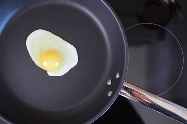 One egg frying on the hot pan, top view - Fotó, kép