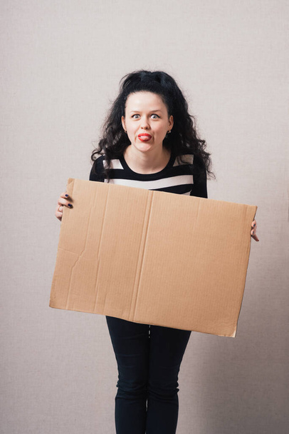 A woman holds a blank kraft paperboard. Gray background - Foto, Imagen