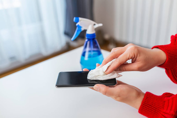 Woman hands with Alcohol Sanitizer mobile phone prevent the virus and bacterias, Hygiene concept. Woman disinfecting the mobile phone by spraying a blue sanitizer from a bottle.Prevent covid19, corona virus. - Photo, Image