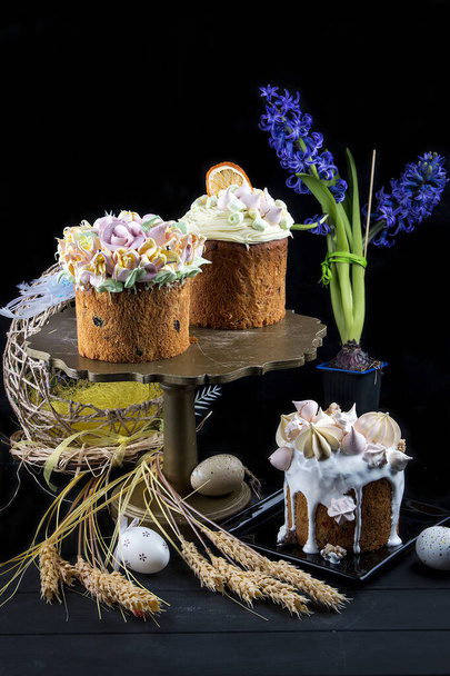 Easter cake kulich. Traditional Easter sweet bread decorated meringue and  candy cane shape eggs on plate on wooden table background - Photo, Image