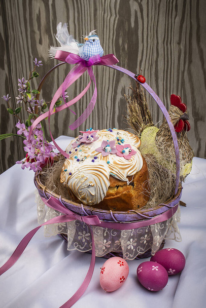 Decorative Easter basket with cake and colored eggs. On a wooden table  - Fotografie, Obrázek