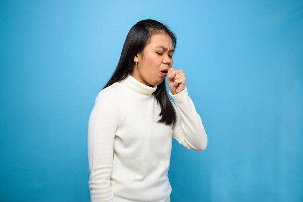 Portrét mladé krásné asijské ženy s bílým tričkem s modrým izolovaným pozadím, kašel v důsledku příznaků viru korony, Covid-19, kašel coronavirus - Fotografie, Obrázek