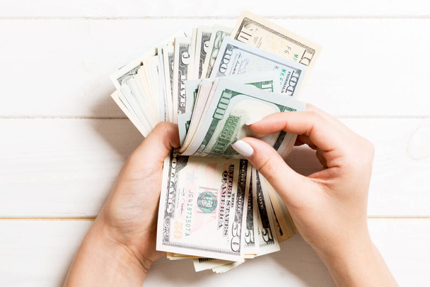 Businesswoman's hands counting one hundred and various dollar bills on wooden background. Salary and wage concept. Top view of Investment concept. - Foto, imagen