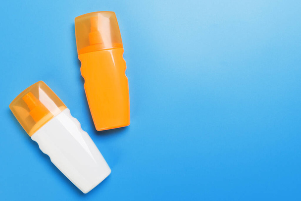 flat lay concept of summer travel vacation. Sunscreen bottle mock up on blue background top view with copy space. - Photo, Image
