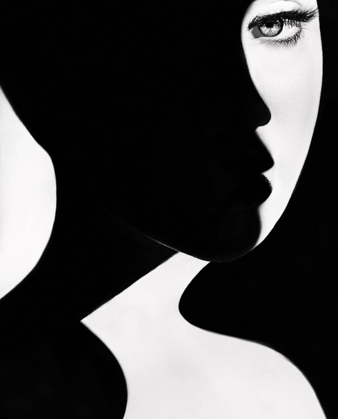 High contrast black and white portrait of a beautiful girl. Girl's face with shadow. Good and evil concept. Fine art concept. Fashion portrait. Dark side person. Good and bad concept. beauty portrait - Фото, изображение