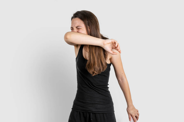 Young woman sneezing to elbow. Pneumonia or virus sickness. Covid-19 pandemic - Fotografie, Obrázek