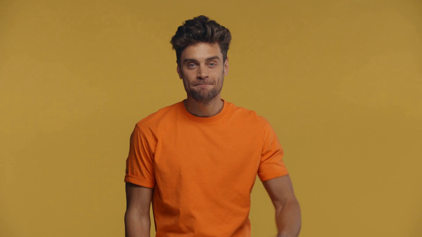 Smiling man waving and inviting at camera isolated on yellow - Metraje, vídeo