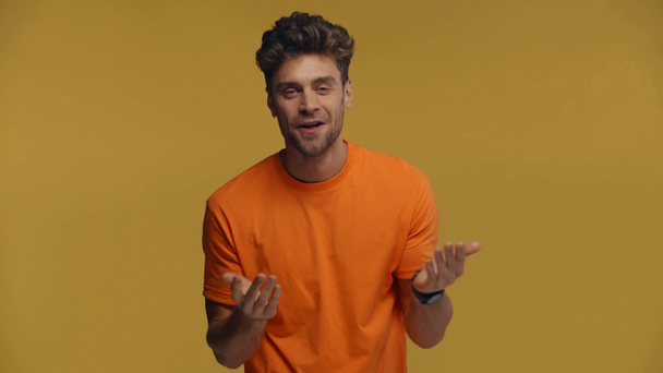 Hombre sorprendido mostrando como gesto en la cámara aislado en amarillo
 - Metraje, vídeo