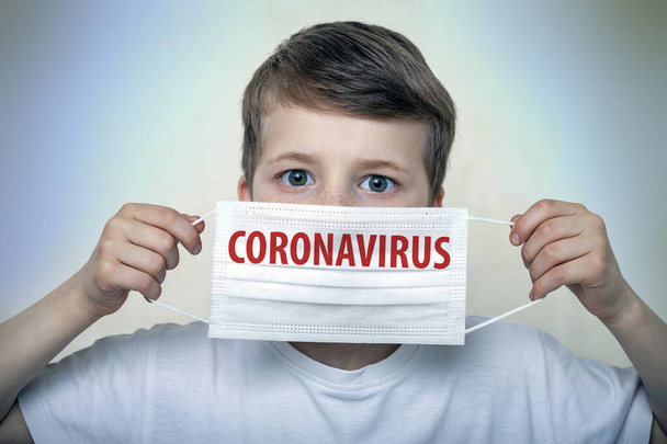 Studio portrait of a boy in a mask on a gray background. Concept of fight against the coronavirus epidemic and proper prevention of infections - Foto, Imagen