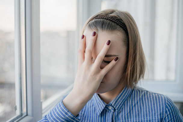 młoda atrakcyjna kobieta cierpiąca na depresję i stres stojąc samotnie w bólu i żalu przed oknem smutna i zdesperowana w domu z podświetleniem studia - Zdjęcie, obraz