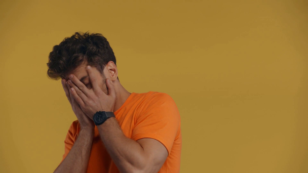 Rémült ember takaró arc kezek elszigetelt sárga - Felvétel, videó