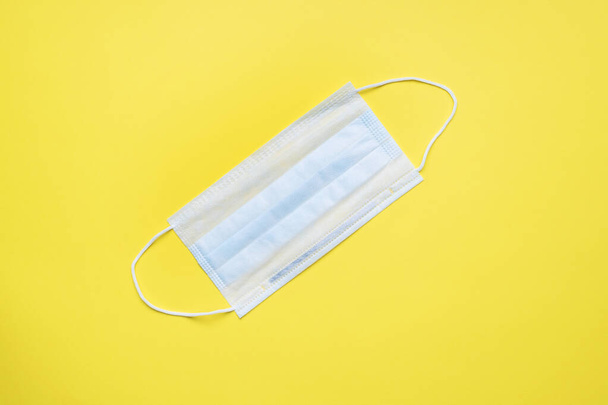 Disposable medical face masks. The concept of prevention of the virus. Yellow background. Copy space - 写真・画像