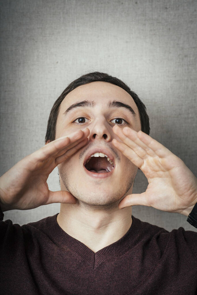 young man shouts in photo studio background - Photo, image