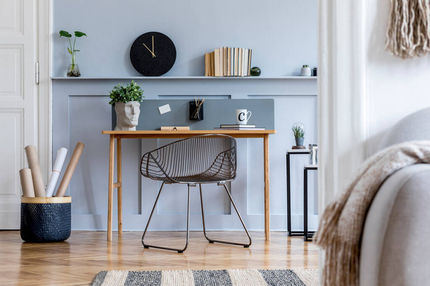 Scandinavian home office interior with wooden desk, design chair, wood panleing with shelf, plant, table lamp, carpet, office supplies and elegant accessories in modern home decor. - Photo, image