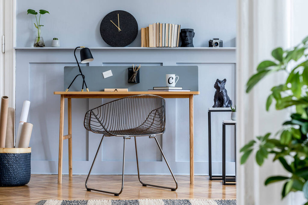 Scandinavian home office interior with wooden desk, design chair, wood panleing with shelf, plant, table lamp, office supplies and elegant accessories in modern home decor. - Фото, изображение