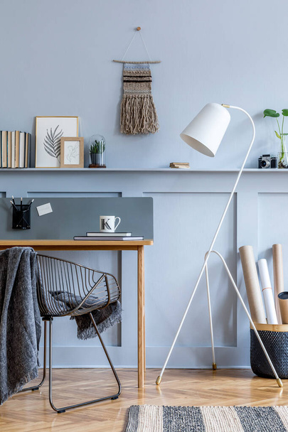 Stylish scandinavian home office with wooden desk, chair, design lamp, office supplies, black basket, plant and personal accessories in modern home decor. - Photo, Image