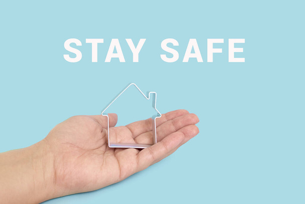 Aufschrift STAY SAFE mit Haus auf blauem Hintergrund. Motivationsbanner für die Selbstisolation während der Coronavirus-Pandemie covid-19 - Foto, Bild