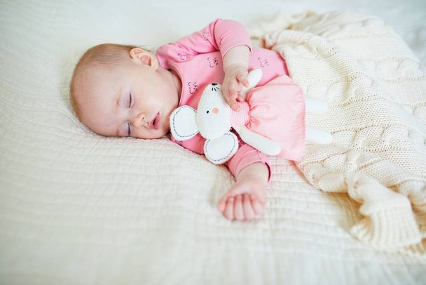 Vauva tyttö ottaa nokoset hänen suosikki hiiri lelu. Pieni lapsi nukkuu sängyssä lohduttajan kanssa. Unikoulutus. Pikkulapsi aurinkoisessa lastenhuoneessa - Valokuva, kuva
